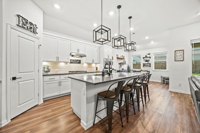 1224 Caprock Dr, Forney, TX 75126 - kitchen with dark countertops, wood finished floors, under cabinet range hood, recessed lighting, and stainless steel gas cooktop