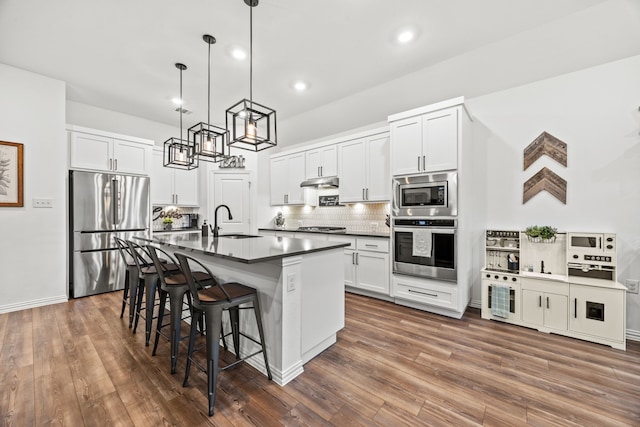 1224 Caprock Dr, Forney, TX 75126 - kitchen featuring stainless steel appliances, dark countertops, a kitchen bar, tasteful backsplash, and an island with sink