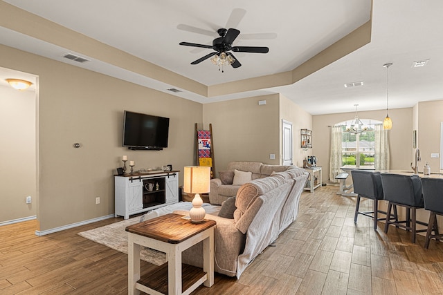 105 Mission Crest Cir, Lindale, TX 75771 - living room featuring light wood finished floors, a chandelier, a ceiling fan, a raised ceiling, and baseboards