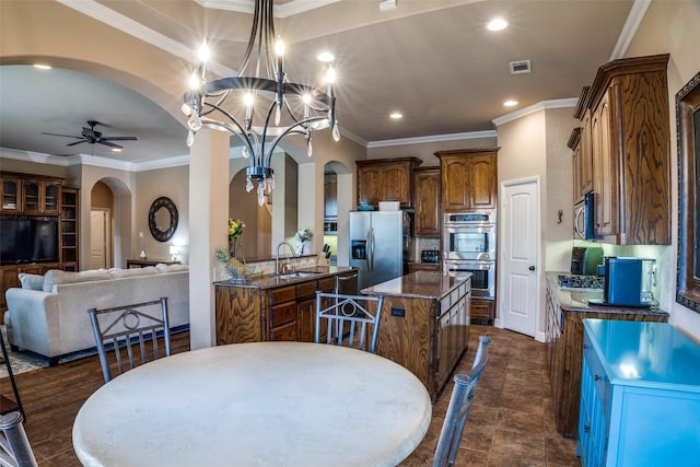 3420 Grayson Ct, Hurst, TX 76054 - kitchen featuring arched walkways, appliances with stainless steel finishes, a kitchen island, crown molding, and a ceiling fan