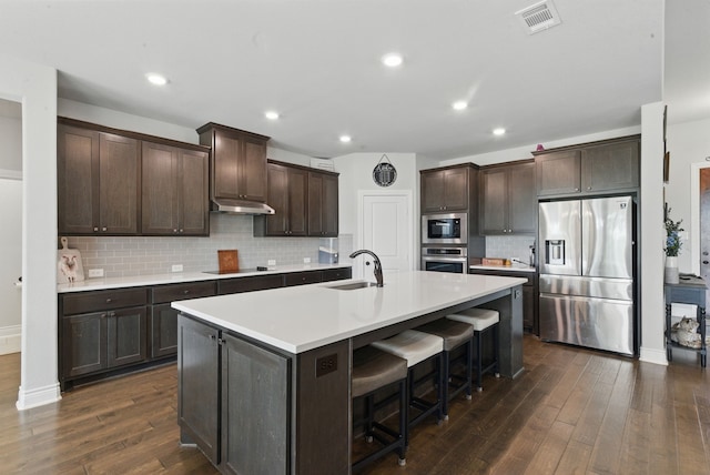 3385 Dps Tower Rd, Perrin, TX 76486 - kitchen with stainless steel appliances, dark wood finished floors, dark brown cabinets, tasteful backsplash, and a kitchen island with sink