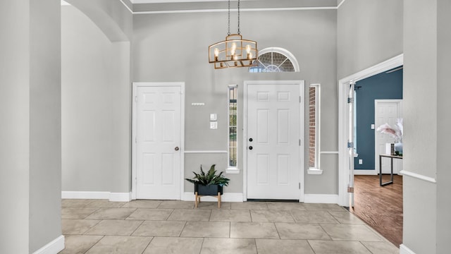 5709 Courtney Cir, Haltom City, TX 76137 - foyer featuring tile patterned floors, a towering ceiling, a chandelier, baseboards, and arched walkways