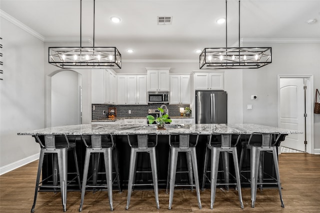386 Cavitt Ct, Robinson, TX 76706 - kitchen with stainless steel appliances, a spacious island, white cabinets, arched walkways, and ornamental molding