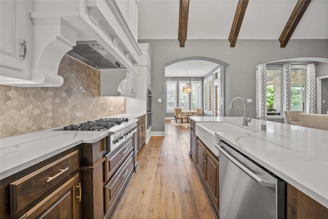 6286 Brentway Rd, Frisco, TX 75034 - kitchen featuring stainless steel appliances, a sink, light wood-type flooring, beam ceiling, and arched walkways