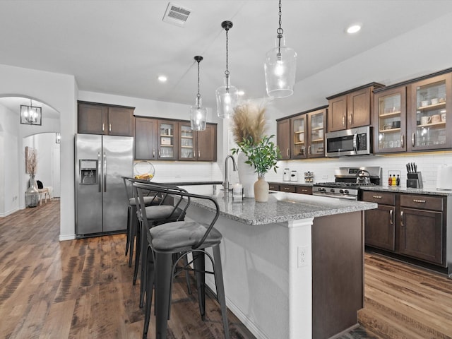 4148 Agatha Ln, Celina, TX 76227 - kitchen with stainless steel appliances, arched walkways, an island with sink, tasteful backsplash, and hanging light fixtures