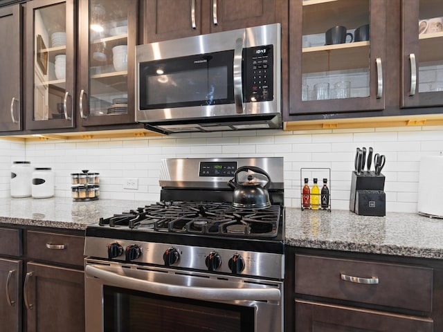 4148 Agatha Ln, Celina, TX 76227 - kitchen featuring stainless steel appliances, dark brown cabinetry, light stone counters, and glass insert cabinets