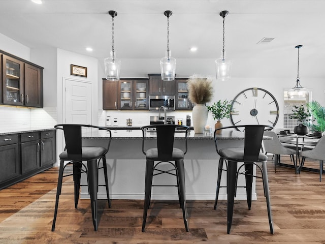 4148 Agatha Ln, Celina, TX 76227 - kitchen featuring stainless steel microwave, a breakfast bar, recessed lighting, backsplash, and dark brown cabinets