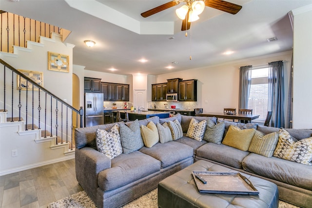 4012 Gennaker Dr, Denton, TX 76210 - living room with light wood-type flooring, ceiling fan, stairway, and crown molding