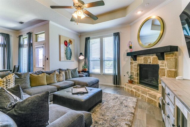 4012 Gennaker Dr, Denton, TX 76210 - living room featuring wood finished floors, ceiling fan, a raised ceiling, a stone fireplace, and ornamental molding