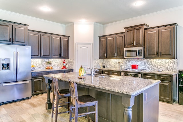 4012 Gennaker Dr, Denton, TX 76210 - kitchen featuring stainless steel appliances, light stone counters, a breakfast bar, dark brown cabinetry, and tasteful backsplash