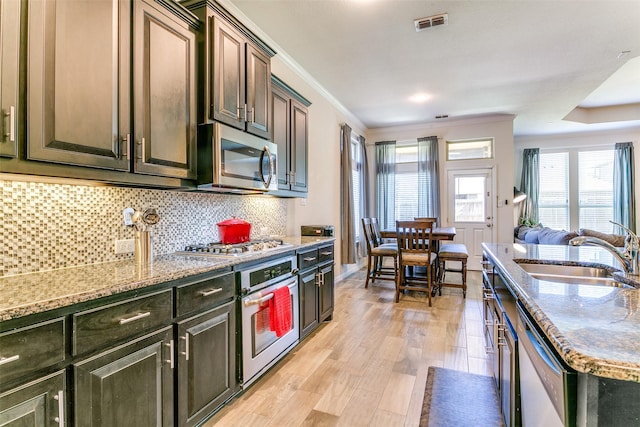 4012 Gennaker Dr, Denton, TX 76210 - kitchen with stainless steel appliances, light wood-style floors, crown molding, light stone counters, and backsplash