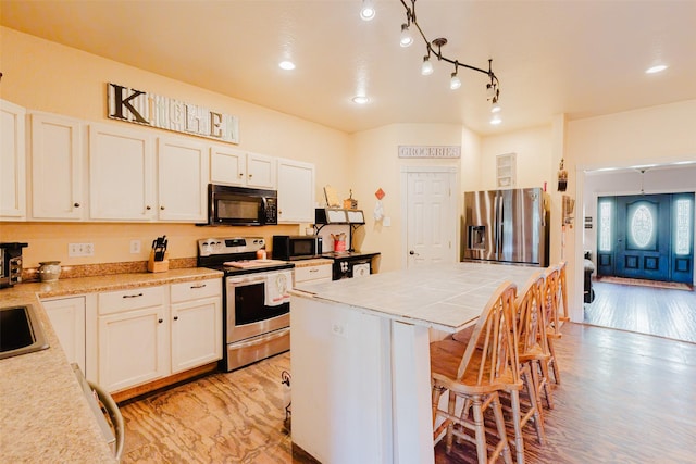 239 County Road 3586, Paradise, TX 76073 - kitchen featuring appliances with stainless steel finishes, a kitchen bar, tile countertops, a sink, and recessed lighting