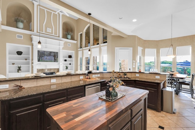 11667 Bent Creek Trl, Frisco, TX 75033 - kitchen with wood counters, a kitchen island, light tile patterned flooring, built in shelves, and hanging light fixtures