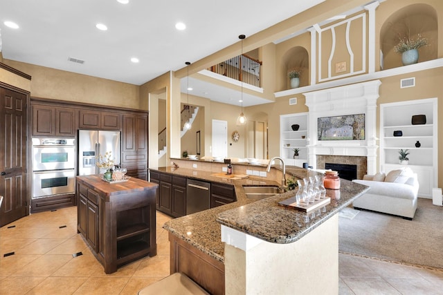 11667 Bent Creek Trl, Frisco, TX 75033 - kitchen featuring appliances with stainless steel finishes, light tile patterned floors, butcher block counters, a spacious island, and dark brown cabinetry