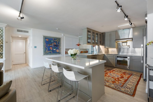 3310 Fairmount St Unit 16B, Dallas, TX 75201 - kitchen with oven, wall chimney exhaust hood, gray cabinets, and rail lighting