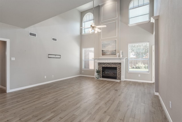 4109 Barnsley Dr, Plano, TX 75093 - unfurnished living room with high vaulted ceiling, light wood-style floors, a stone fireplace, baseboards, and a ceiling fan