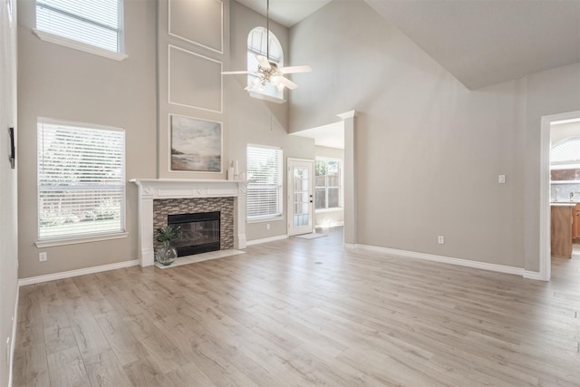 4109 Barnsley Dr, Plano, TX 75093 - unfurnished living room featuring a towering ceiling, light wood-style floors, a ceiling fan, a stone fireplace, and baseboards