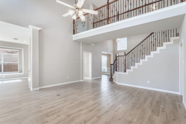4109 Barnsley Dr, Plano, TX 75093 - unfurnished living room featuring a towering ceiling, stairs, light wood finished floors, ceiling fan, and baseboards