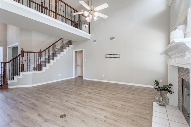 4109 Barnsley Dr, Plano, TX 75093 - unfurnished living room with a high ceiling, stairway, ceiling fan, light wood-style floors, and a tile fireplace