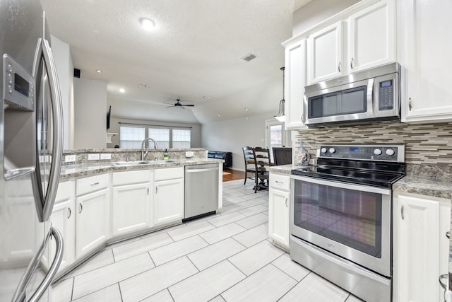 1629 Big Bend Dr, Lewisville, TX 75077 - kitchen with stainless steel appliances, a sink, a ceiling fan, a peninsula, and decorative backsplash