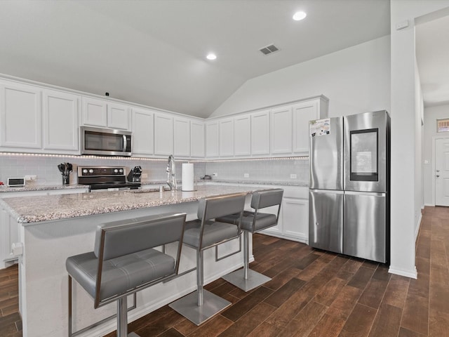 4204 Cordata Dr, Melissa, TX 75454 - kitchen featuring appliances with stainless steel finishes, dark wood-style flooring, lofted ceiling, decorative backsplash, and white cabinets