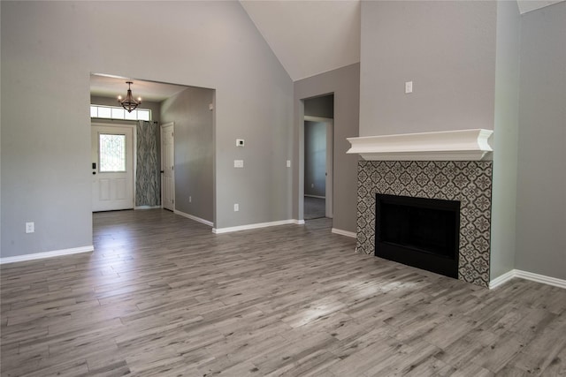 103 Saddle Club Rd, Weatherford, TX 76088 - unfurnished living room featuring wood finished floors, a chandelier, high vaulted ceiling, a tiled fireplace, and baseboards