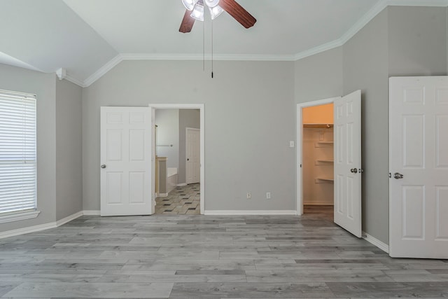 6937 Andress Dr, Fort Worth, TX 76132 - unfurnished bedroom with a walk in closet, vaulted ceiling, multiple windows, baseboards, and light wood-style flooring