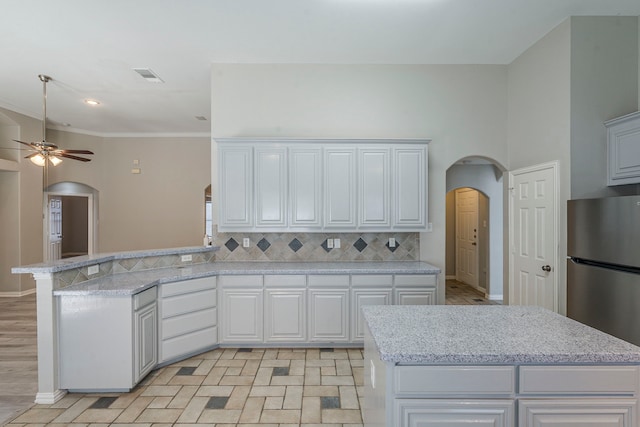 6937 Andress Dr, Fort Worth, TX 76132 - kitchen featuring arched walkways, freestanding refrigerator, ceiling fan, decorative backsplash, and a peninsula