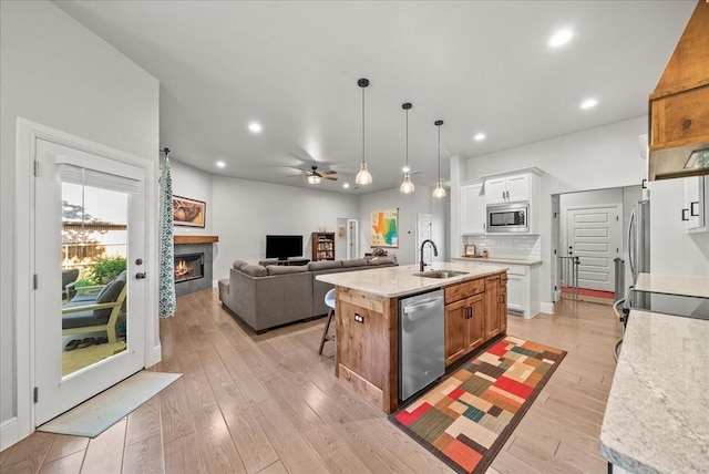 184 Lakeview Cir, Pilot Point, TX 76258 - kitchen with appliances with stainless steel finishes, a sink, a lit fireplace, a ceiling fan, and a center island with sink