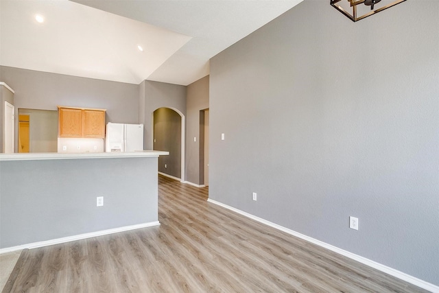 9805 Rockledge Rd, Fort Worth, TX 76108 - unfurnished living room with arched walkways, baseboards, light wood-type flooring, and lofted ceiling