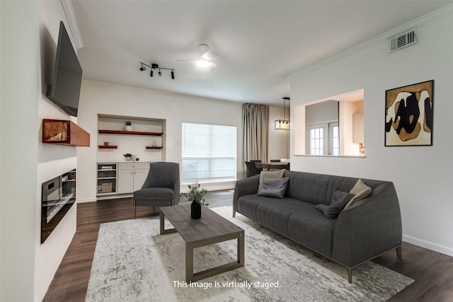 8601 Park Ln Unit 111, Dallas, TX 75231 - living area featuring ornamental molding, ceiling fan, dark wood-style floors, a glass covered fireplace, and baseboards