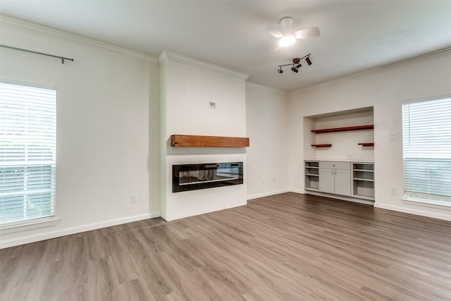 8601 Park Ln Unit 111, Dallas, TX 75231 - unfurnished living room featuring wood finished floors, a glass covered fireplace, ornamental molding, and healthy amount of natural light