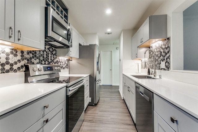 8601 Park Ln Unit 111, Dallas, TX 75231 - kitchen with appliances with stainless steel finishes, a sink, backsplash, light countertops, and light wood-type flooring