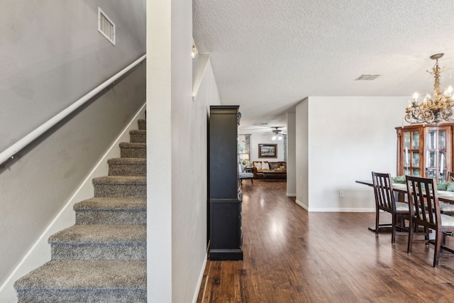 2300 Avalon Creek Way, Mckinney, TX 75071 - staircase with wood finished floors, a chandelier, a textured ceiling, a ceiling fan, and baseboards