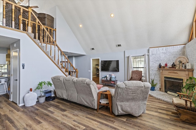 500 W San Diego St, Detroit, TX 75436 - living room featuring high vaulted ceiling, stairs, a brick fireplace, and wood finished floors