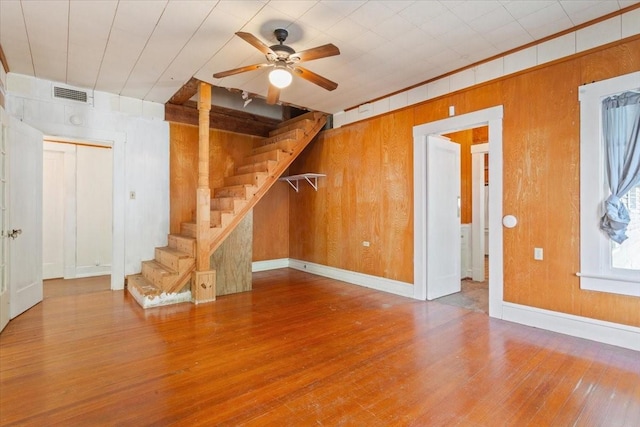 2600 Colcord Ave, Waco, TX 76707 - unfurnished living room with wood walls, hardwood / wood-style floors, stairway, a ceiling fan, and baseboards