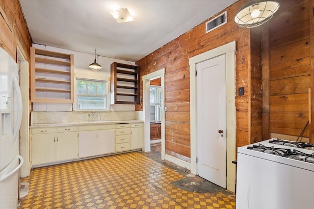 2600 Colcord Ave, Waco, TX 76707 - kitchen featuring a sink, light countertops, white appliances, light floors, and wood walls