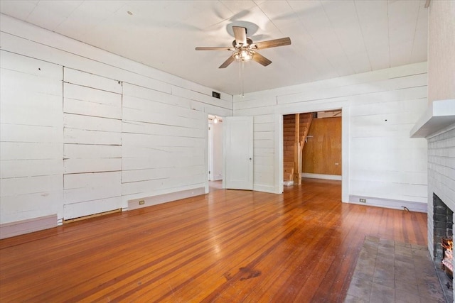 2600 Colcord Ave, Waco, TX 76707 - unfurnished living room featuring ceiling fan, a brick fireplace, hardwood / wood-style floors, and wood walls
