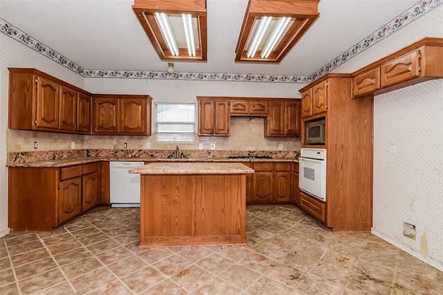 4005 Cavalier Dr, Rowlett, TX 75088 - kitchen featuring white appliances, wallpapered walls, brown cabinets, a kitchen island, and a sink