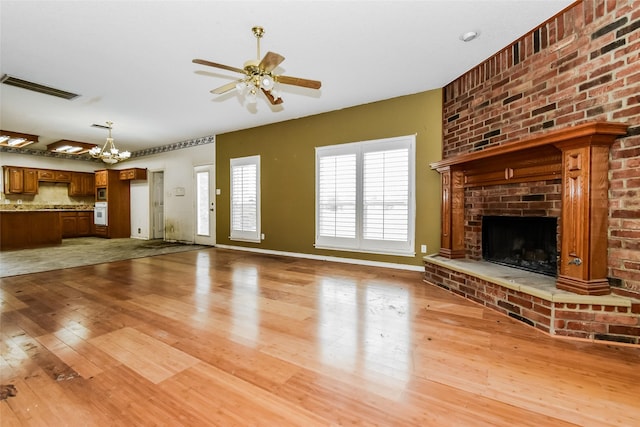 4005 Cavalier Dr, Rowlett, TX 75088 - unfurnished living room featuring light wood-style floors, ceiling fan, a chandelier, a brick fireplace, and baseboards