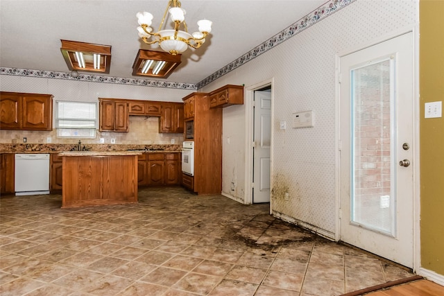 4005 Cavalier Dr, Rowlett, TX 75088 - kitchen featuring white appliances, a chandelier, a sink, brown cabinetry, and wallpapered walls