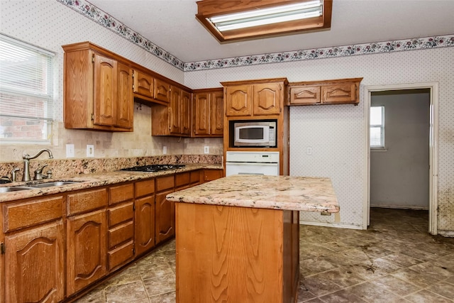 4005 Cavalier Dr, Rowlett, TX 75088 - kitchen featuring built in microwave, white oven, a sink, gas cooktop, and wallpapered walls