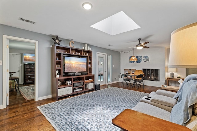 2816 Nottingham Dr, Denton, TX 76209 - living room featuring a skylight, a ceiling fan, a fireplace, dark wood finished floors, and baseboards