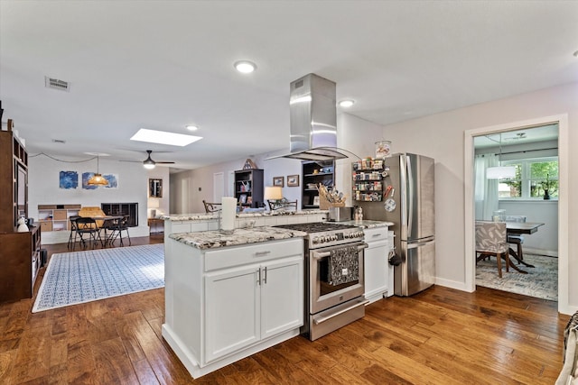 2816 Nottingham Dr, Denton, TX 76209 - kitchen featuring appliances with stainless steel finishes, island range hood, a peninsula, open floor plan, and dark wood-style flooring