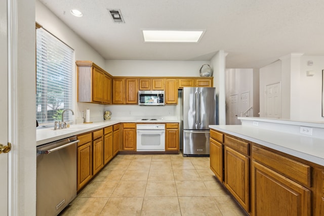 102 Pinion Dr, Euless, TX 76039 - kitchen with appliances with stainless steel finishes, a sink, light countertops, and brown cabinets