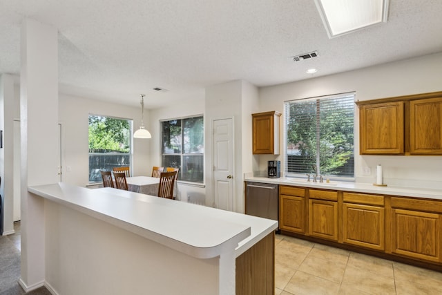 102 Pinion Dr, Euless, TX 76039 - kitchen featuring dishwasher, brown cabinets, light countertops, a sink, and a textured ceiling