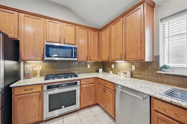 12315 Red Hawk Dr, Frisco, TX 75033 - kitchen with appliances with stainless steel finishes, vaulted ceiling, tasteful backsplash, and light stone counters