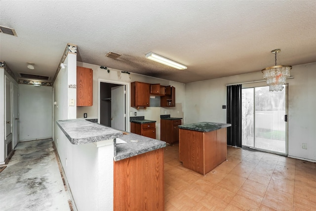 7922 Jubilant Dr, Dallas, TX 75237 - kitchen with a peninsula, brown cabinets, a textured ceiling, a center island, and a chandelier