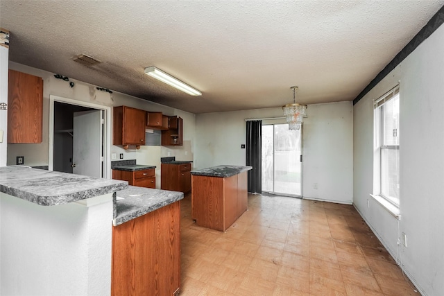 7922 Jubilant Dr, Dallas, TX 75237 - kitchen with light floors, brown cabinets, a peninsula, a textured ceiling, and a center island