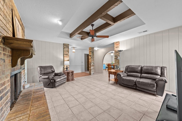 204 Glenwick Pl, Allen, TX 75013 - living area featuring a ceiling fan, a brick fireplace, light tile patterned floors, wooden walls, and beamed ceiling